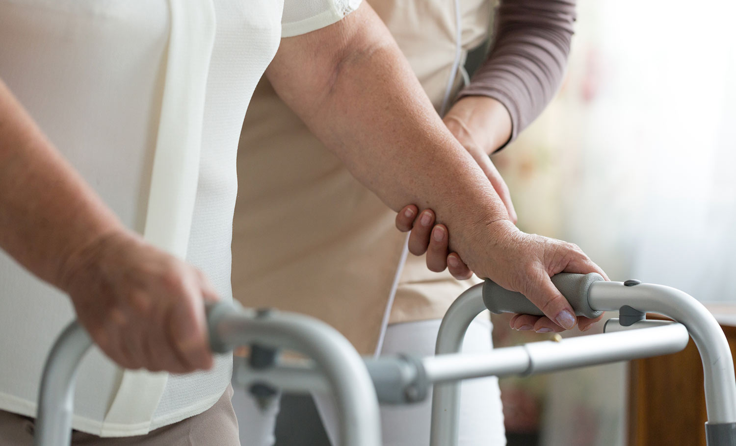 caretaker assisitng woman with a walker