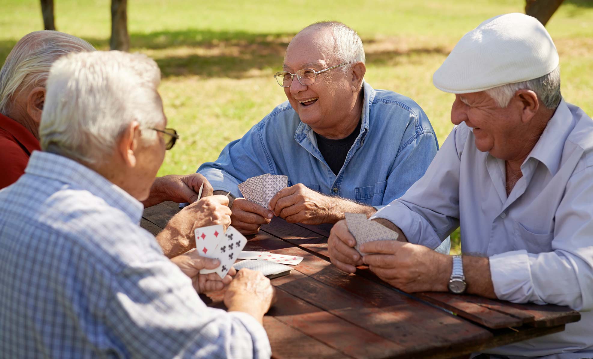 Group of senior men playing cards outside