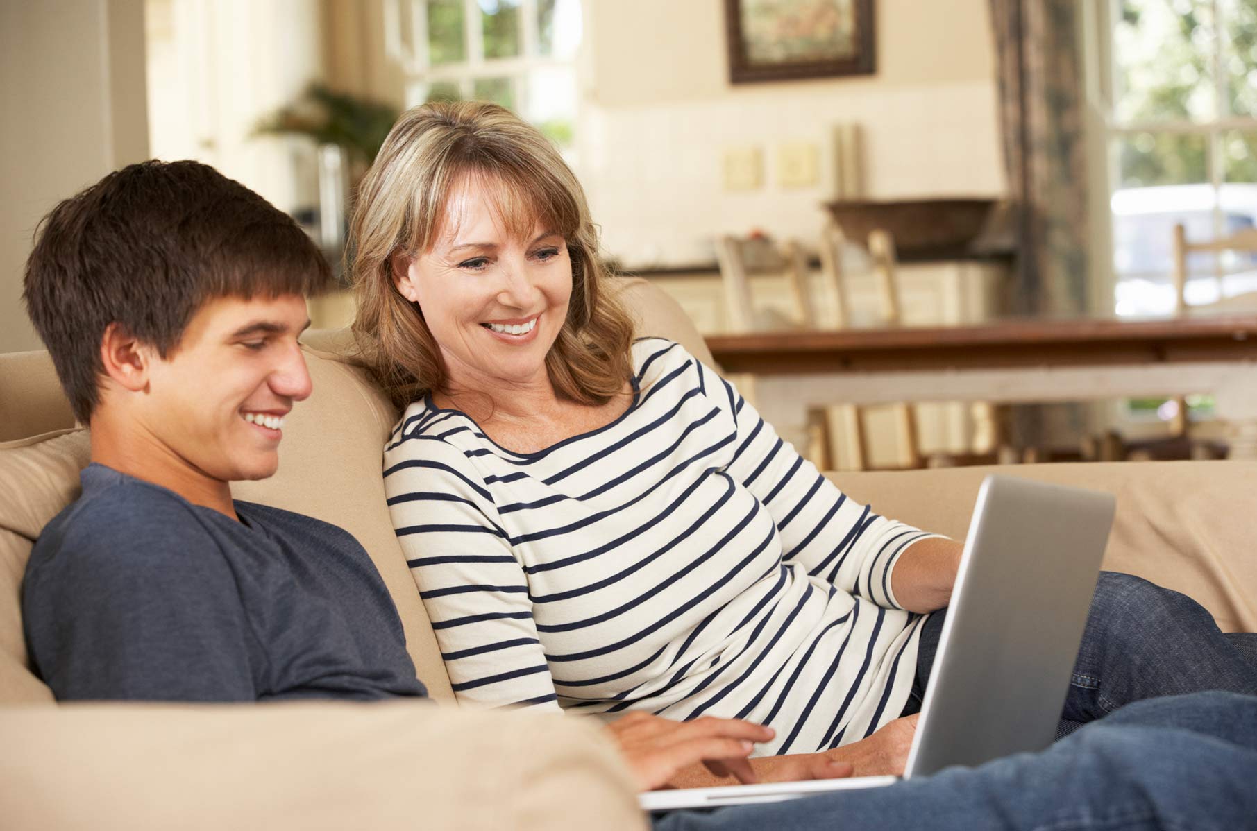 teenage son with his mother on a laptop viewing patient portal