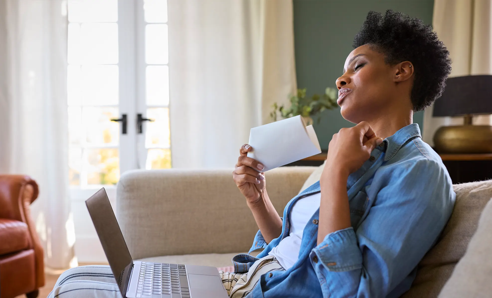 Woman fanning herself on the couch due to a hot flash