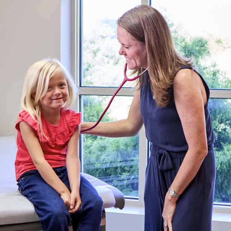 Pediatrician using a stethoscope to examine a young patient