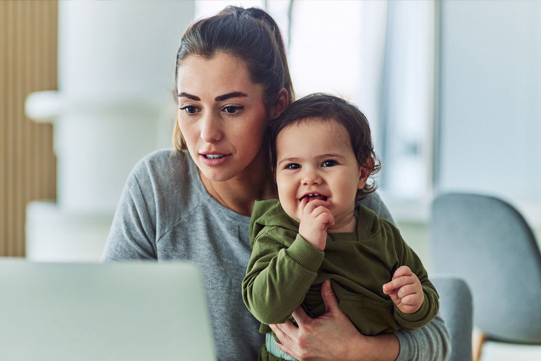 Mom with baby looking up insurance plans on laptop