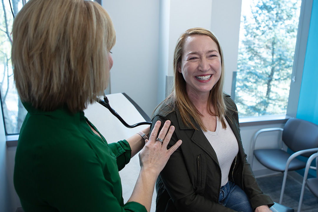 Primary care provider listening to a patient's lungs with a stethoscope during an exam